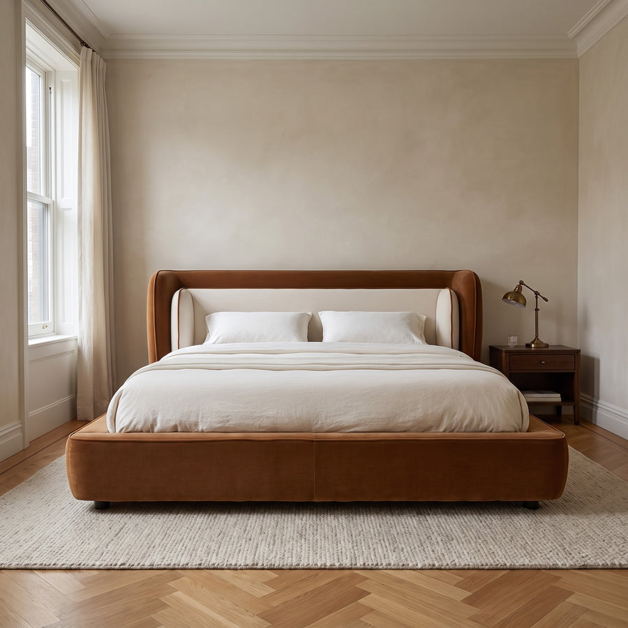 Cognac and off-white wingback bed in a pre-war bedroom with herringbone floor and crown molding, soft overcast morning light.